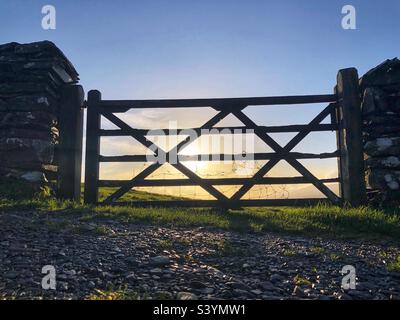 Ländliches Holztor mit Hintergrundbeleuchtung und niedriger Herbstsonne, Lake District England Stockfoto