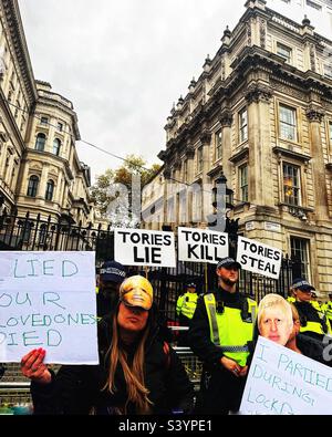 Demonstranten außerhalb der Downing Street, Heimat des britischen Premierministers und der Regierung. Auf den Plakaten steht, dass Tories lügen, töten und stehlen. Maskierte Demonstranten kritisieren Lockdown-Einhaltung und Heuchelei Stockfoto
