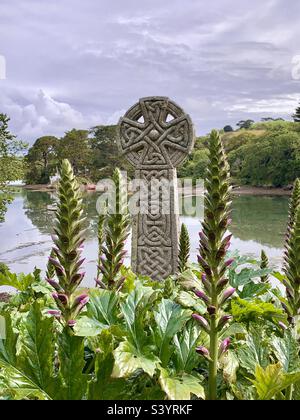 Dekorativ geschnitzte Steine Celtic kreuzen Grabstein in St. Just in Roseland Church Cemetery mit Blick auf den Fluss an einem heißen Sommertag in Cornwall, England Stockfoto