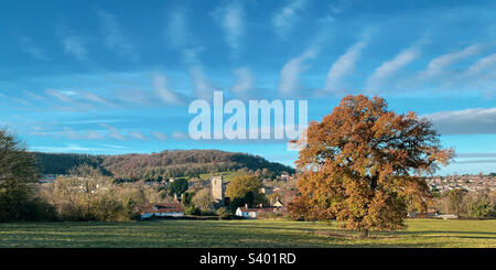Die Farben des Spätherbstes und die atemberaubende Wolkenbildung in einer typischen Kirchenszene in Gloucestershire. Ein Mobiltelefon-Foto mit Post Processing auf einem Telefon oder Tablet. Stockfoto