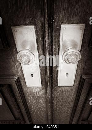 Alte Türknöpfe aus Metall an einem alten Gebäude in Manhattan, New York. Foto in Schwarz-Weiß mit einem Teil der Holztüren. Stockfoto