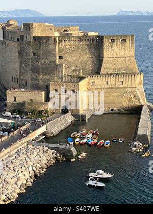 Farbenfrohe Boote vor der Burg Ovo (Castel dell'Ovo) in Neapel, Italien. Stockfoto