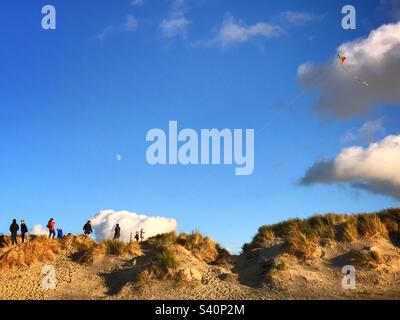 Familie, die einen Drachen auf den Sanddünen in East Head, West Wittering Beach, West Sussex, Großbritannien, fliegt Stockfoto