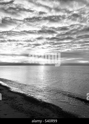 Sonnenstrahlen, die durch Wolkenschichten scheinen. Atlantik und Strand. Stockfoto