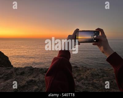 Den Sonnenuntergang mit einem Smartphone fotografieren Stockfoto