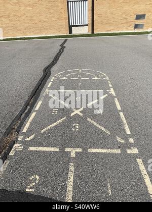 Erinnert an die Kindheit vor Jahrzehnten, bleibt dieser Hopscotch, dieser Platz auf dem Spielplatz, wie auch die Grundschule selbst. Stockfoto