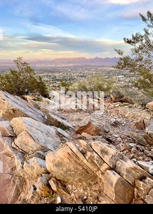 Die schrägen Felsen von Two Bit Peak und Kreosote Büsche umrahmen den pastellfarbenen Himmel, den Norden von Scottsdale und die McDowell Mountains bei Sonnenuntergang, Phoenix Mountain Preserve, Arizona Stockfoto