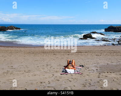 Eine Frau genießt Zeit allein an einem ruhigen Strand in der Nähe von Montezuma in Costa Rica Stockfoto