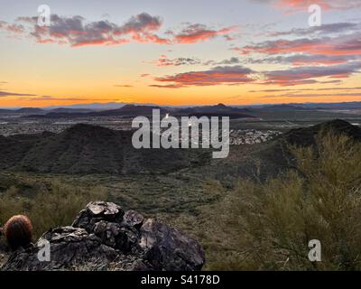 Desert Vista Trailhead, Sonoran Preserve, Blick von felsigen Felsvorsprüngen, Sonnenuntergang in Arizona, der sich über dem Kanal reflektiert und zwei Leuchtfeuer in der Ferne erzeugt, goldener Himmel, rot und violett verstreute Wolken Stockfoto