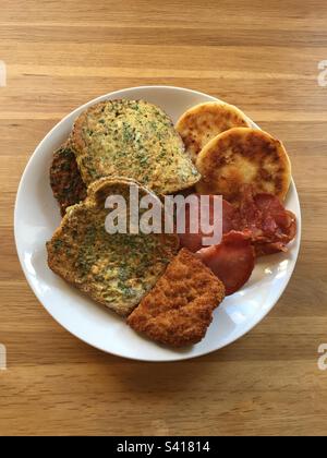 Braten Sie das Mittagessen mit Eierbrot, knusprigem Speck, Huhn in Brotkrumen und Kartoffelkuchen, Abb. 6. Stockfoto