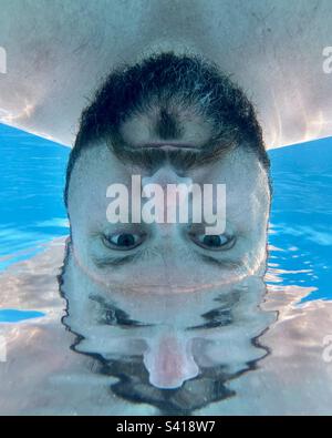 Abstraktes Unterwasserfoto eines bärtigen Mannes im Swimmingpool. Stockfoto