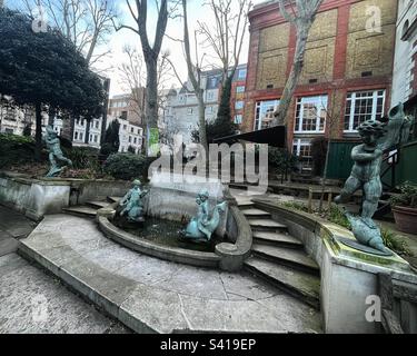 St. James's Church in Piccadilly ein Brunnen wurde von Masons nach dem Entwurf von Alfred Hardiman RA errichtet. Der Steinbrunnen mit Cherubs, Delfinen und einem elliptischen Steinbecken, flankiert von Stufen - gelistet Stockfoto