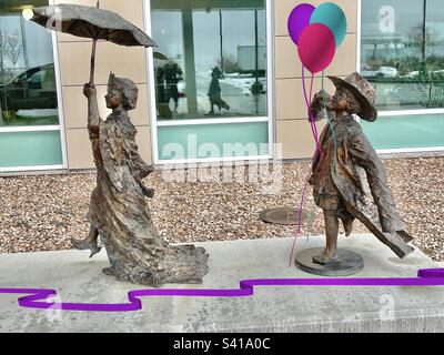 Liebenswerte Statuen von Kindern, die sich verkleiden und ihrer Fantasie freien Lauf lassen, einfach nur Spaß haben. Dekorative Bänder und Ballons wurden digital hinzugefügt und ergänzen die Laune des Stücks. Stockfoto