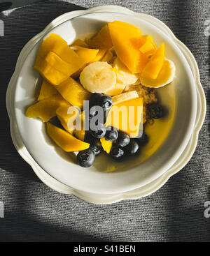 Schüssel Haferflocken mit frischen Mango-, Bananen- und Blaubeeren-Scheiben. Stockfoto
