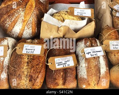 Frische hausgemachte Brotlaibe mit Preisschildern in einem Delikatessengeschäft und einer Schaufensterausstellung für Wurstwaren Stockfoto