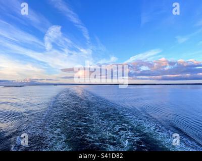 Atemberaubender Blick auf den Sonnenaufgang über dem Meer mit hellem Himmel und sonnenbeleuchteten Wolken vom Schiff Stockfoto