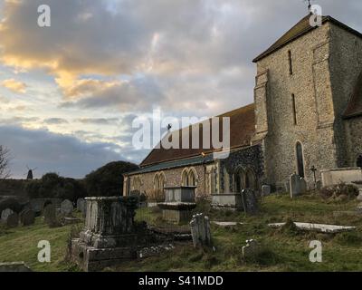 St. Margaret's Church mit Beacon Mill auf dem Hügel im Hintergrund in Rottingdean, East Sussex, England. Stockfoto