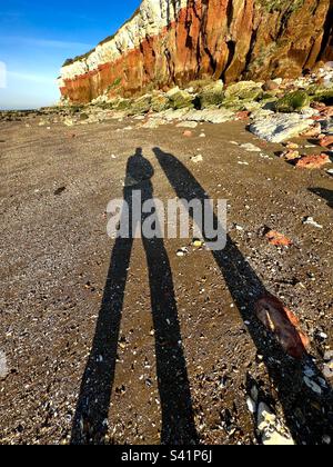 Schatten am Strand unter dem geschichteten karsteinfarbenen roten Kalkstein und den weißen Kreidefelsen in Hunstanton, Norfolk Stockfoto