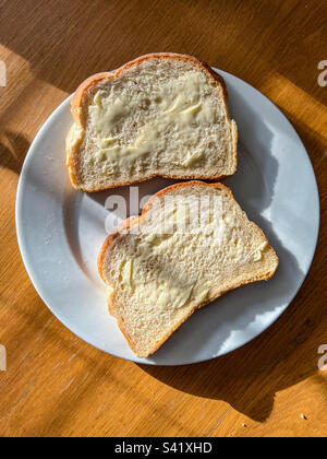 Zwei Scheiben weißes Butterbrot auf weißem Teller Stockfoto