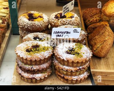 Frangipan-Torte und Fruit Custard Brioche im Schaufenster der Bäckerei Stockfoto