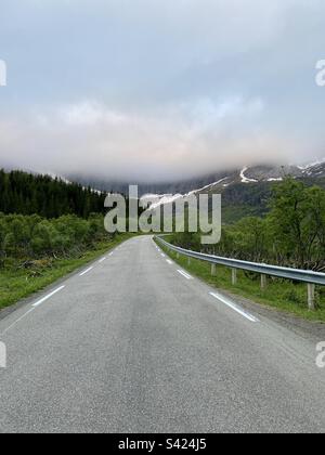 Auf dem Weg zum Nusfjord auf den Lofoten-Inseln, Norwegen. Berggipfel in den Wolken. Foto einer Asphaltstraße. Stockfoto
