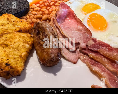 Komplettes englisches Frühstück mit Würstchen, Eiern, Kartoffelrösti, schwarzem Pudding und Bohnen Stockfoto