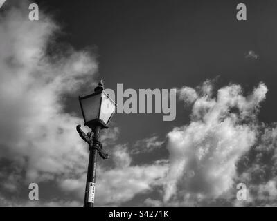 Ein Schwarzweißfoto einer Straßenlampe vor einem bewölkten Himmel Stockfoto