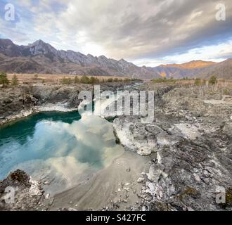 Der Katun-Fluss an der tiefsten Stelle fließt bei Sonnenuntergang in die Ufer des Vulkans im Altai-Gebirge. Stockfoto