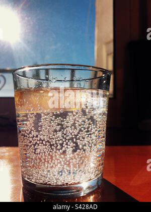 Ein Glas Mineralwasser serviert mit einem Stück Zitrone Stockfoto