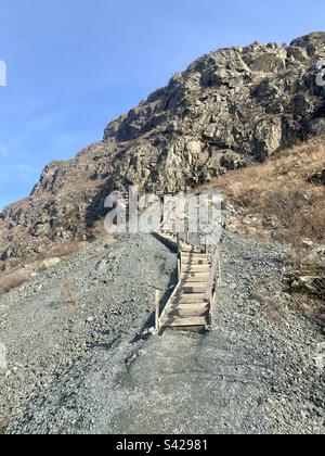 Eine hölzerne Treppe führt zu einer Höhle auf einer Steinklippe im Altai in den alten Minen Sibiriens Stockfoto