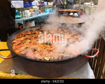 Aus nächster Nähe steigt der Dampf von Paella PAN Cooking Seafood Spanische Paella Street Food auf dem lokalen Bauernmarkt in Großbritannien Stockfoto