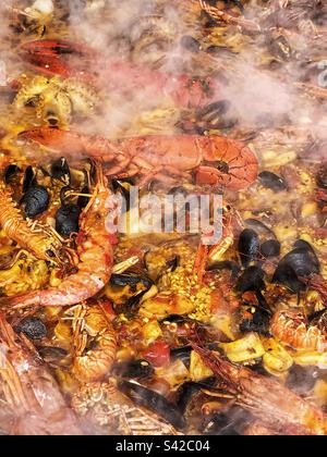 Aus nächster Nähe steigt der Dampf von Paella PAN Cooking Seafood Spanische Paella Street Food auf dem lokalen Bauernmarkt in Großbritannien Stockfoto