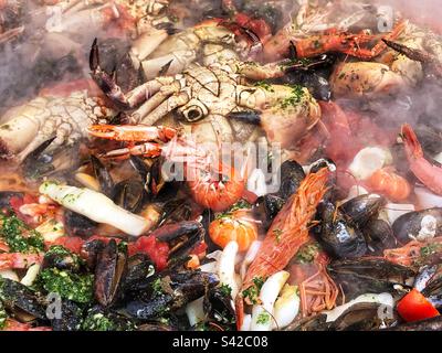 Aus nächster Nähe steigt der Dampf von Paella PAN Cooking Seafood Spanische Paella Street Food auf dem lokalen Bauernmarkt in Großbritannien Stockfoto