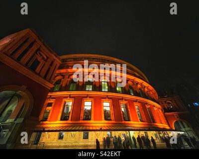 Schlange an den Türen der Royal Albert Hall, eine weiter in der Nacht. Die historische Konzerthalle in Kensington ist beleuchtet Stockfoto