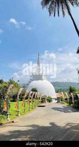 Flatternde buddhistische Flaggen und ruhige Chaitya, ein Symbol des Friedens und der Spiritualität in SriLanka Stockfoto