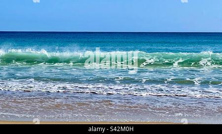 Wellen am Burgau-Strand in Portugal mit klarem blauem Himmel und Horizont Stockfoto