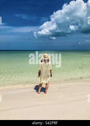 Eine wunderschöne Frau schaut vom Holbox Beach aus auf das faszinierende farbige Meer. Stockfoto