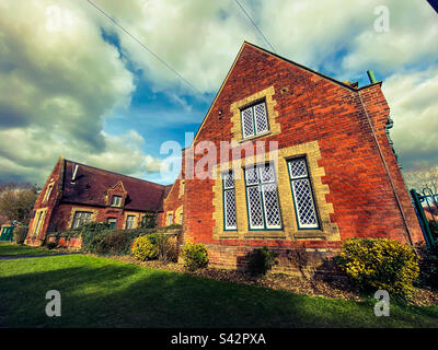 Ein altes traditionelles Schulgebäude in einem kleinen Dorf in der englischen Landschaft in Großbritannien Stockfoto