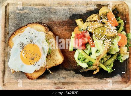 Fantastisches Frühstück - Avocado Toast garniert mit einem sonnigen Ei und Napoleon Gemüse an der Seite. Stockfoto