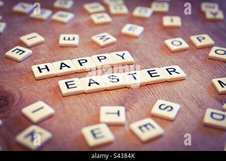 Frohe Ostern, geschrieben in Scrabble-Buchstaben auf einem Küchentisch Stockfoto