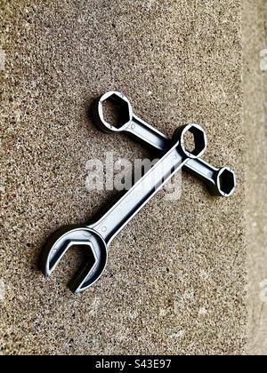 2 graue Schraubenschlüssel in der Mitte des Rahmens mit Zementhintergrund. Einschließlich Druckbereich. Stockfoto