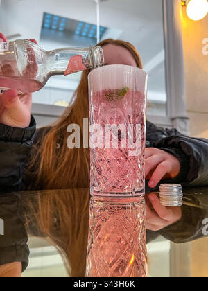 Teenager, der in einer Bar rosa Limonade in Glas gießt Stockfoto