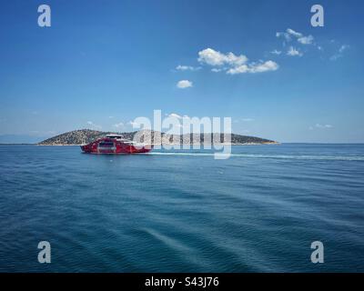 Blick auf das Meer mit Thassopoula und einer roten Fähre, die zur Insel Thassos in Griechenland segelt. Stockfoto