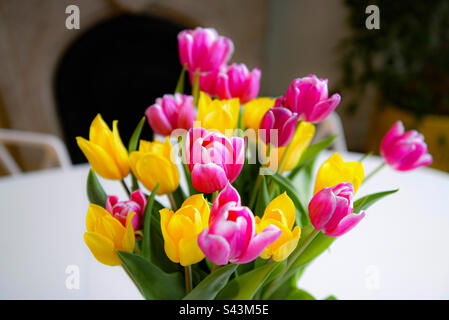 Pinkfarbene und gelbe Tulpen auf einem weißen Tisch Stockfoto