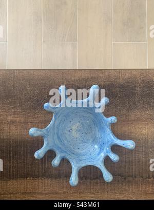 Nahaufnahme einer handbemalten blau-weiß gesprenkelten Keramikschüssel mit Holzhintergrund Stockfoto
