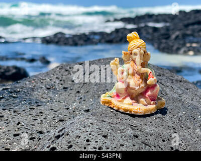 Eine Figur des hinduistischen Gottes Ganesh, die auf Felsen am Strand von Roche Noires, Poste de Flacq, Mauritius, Afrika, platziert wurde Stockfoto