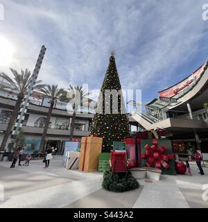 SANTA MONICA, CA, 2022. DEZEMBER: Weihnachtsdekorationen mit riesigem Weihnachtsbaum, und Leute, die in Geschäften im Open-Air-Einkaufszentrum einkaufen Stockfoto