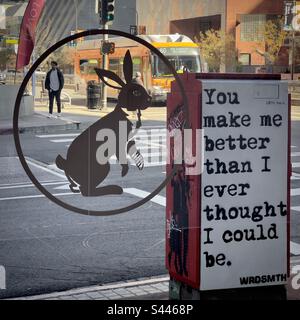 LOS ANGELES, CA, 2022. DEZEMBER: Straßenkunst hinter Kaninchen auf dem Schaufenster des Cafés, Fußgängerzone überquert Straße im Hintergrund, im Downtown Financial District Stockfoto