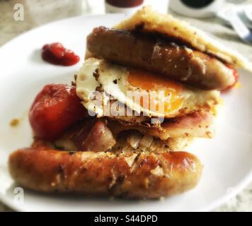 Irisches Soda-Brot mit Würstchen, Ei, Speck und Tomaten auf einem weißen Teller Stockfoto