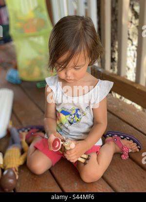 Kleines Mädchen, das mit Toy Story Spielzeugen an Deck spielt. Stockfoto